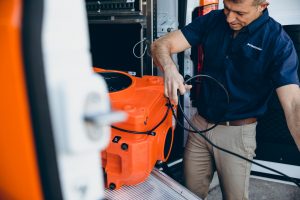 restoration technician taking equipment out of orange van