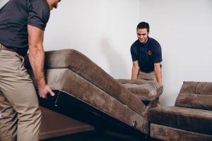 sewage cleanup professionals moving a couch out of harm's way